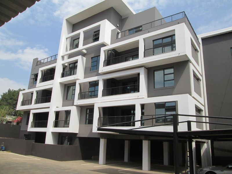 Modern multi-story apartment building featuring contemporary architectural design with private balconies, aluminium windows, and a covered ground-level parking area.