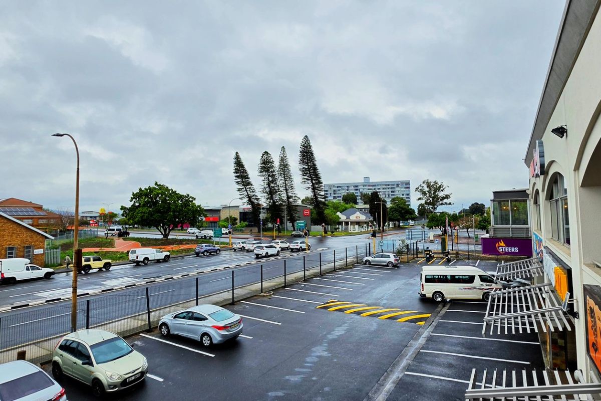 Elevated view of a commercial property parking area and adjacent street intersection under an overcast sky.