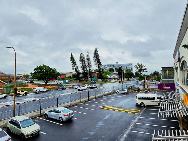 Elevated view of a commercial property parking area and adjacent street intersection under an overcast sky.