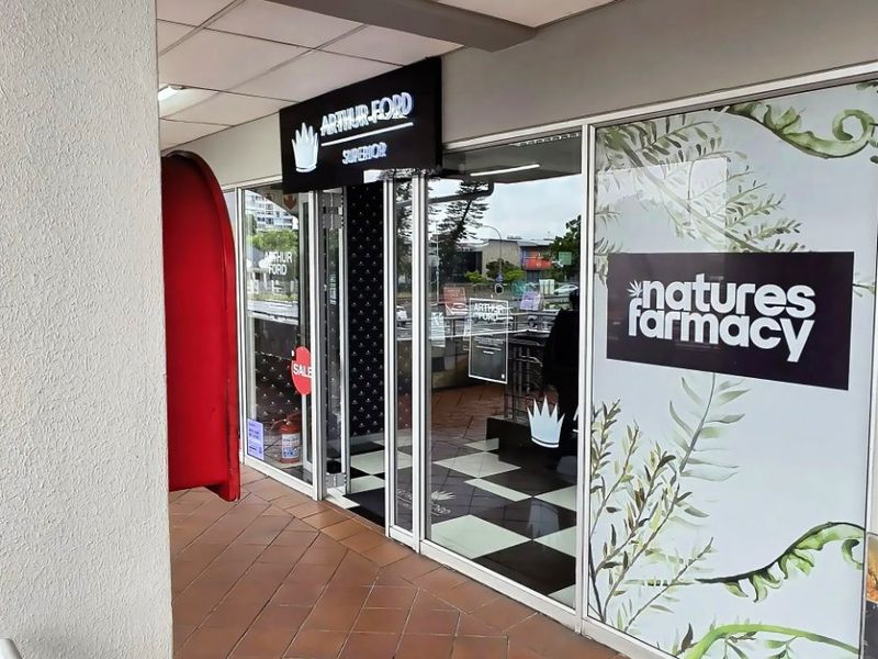 Commercial storefront entrance featuring a glass facade, tiled walkway, and suspended ceiling, suitable for retail or pharmacy use.