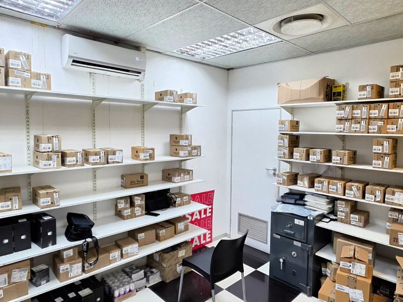 A functional utility or storage room featuring extensive wall-mounted shelving, a built-in safe, split-system air conditioning, and a durable checkered floor.