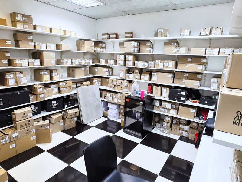 A functional utility or storage room featuring extensive wall-mounted shelving units and a high-contrast black and white tiled floor.