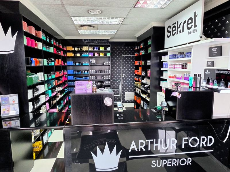 A well-maintained commercial retail space featuring custom built-in shelving, a professional reception counter, and modern recessed lighting throughout the store.