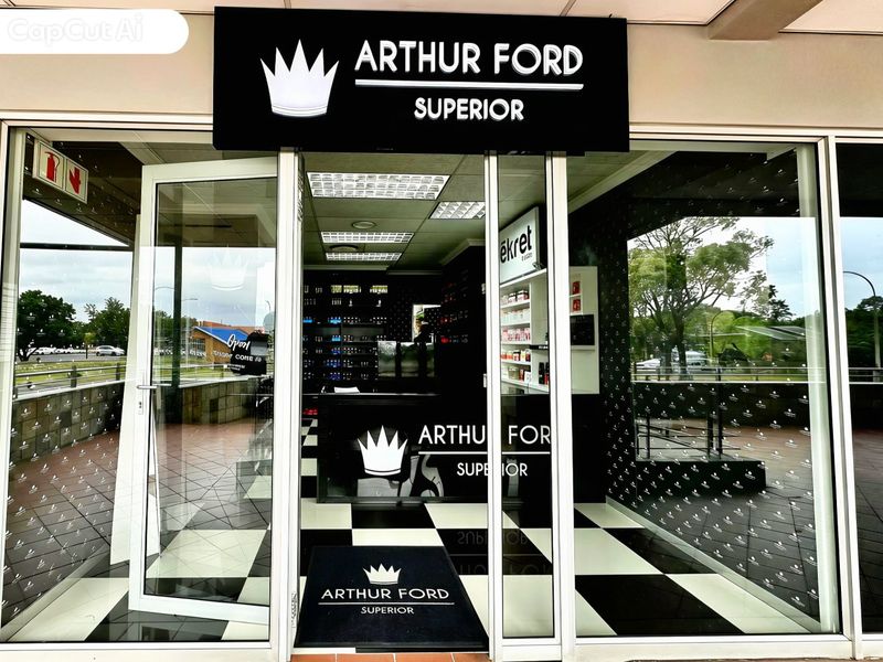 A commercial storefront entrance featuring a glass facade, branded signage, and a modern interior with checkered flooring and built-in display shelving.