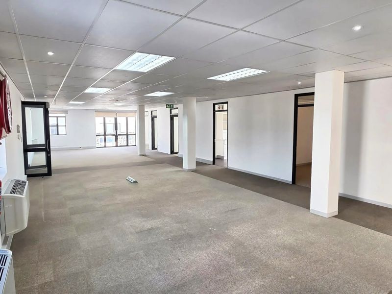 Spacious open-plan commercial office area featuring a suspended ceiling, recessed lighting, carpeted flooring, and integrated climate control systems.