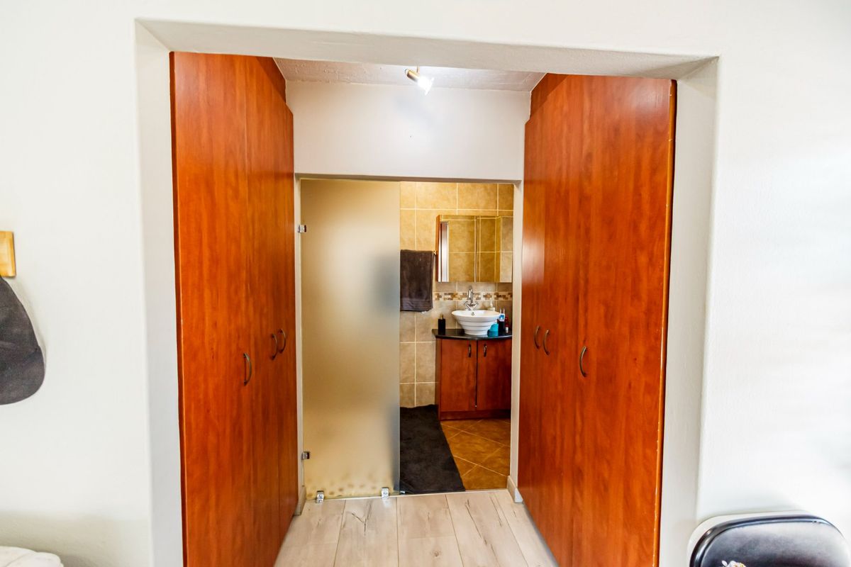 A bathroom entrance featuring built-in wooden cupboards, a frosted glass door, and a vanity with a vessel sink and tiled finishes.