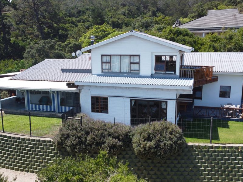 Aerial view of the rear elevation featuring a multi-level design, corrugated metal roofing, a timber balcony, and a covered patio area.