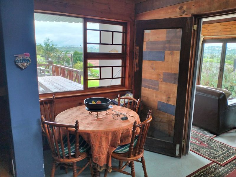 Dining area featuring rustic timber wall cladding, large windows with outdoor views, and direct access to an adjoining living space.
