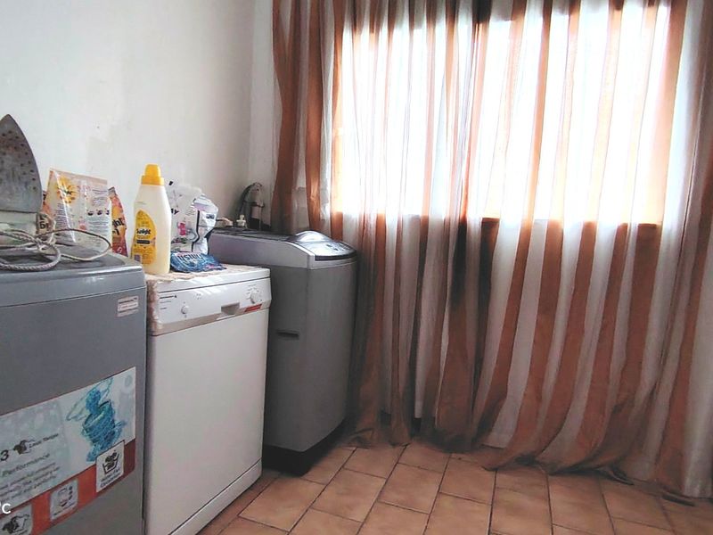 A functional laundry area featuring tiled flooring and window treatments, providing a practical space for household utility tasks.