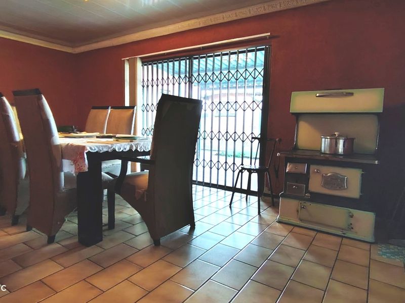 Dining area featuring tiled flooring, a security gate leading to the exterior, and a vintage cast iron stove.