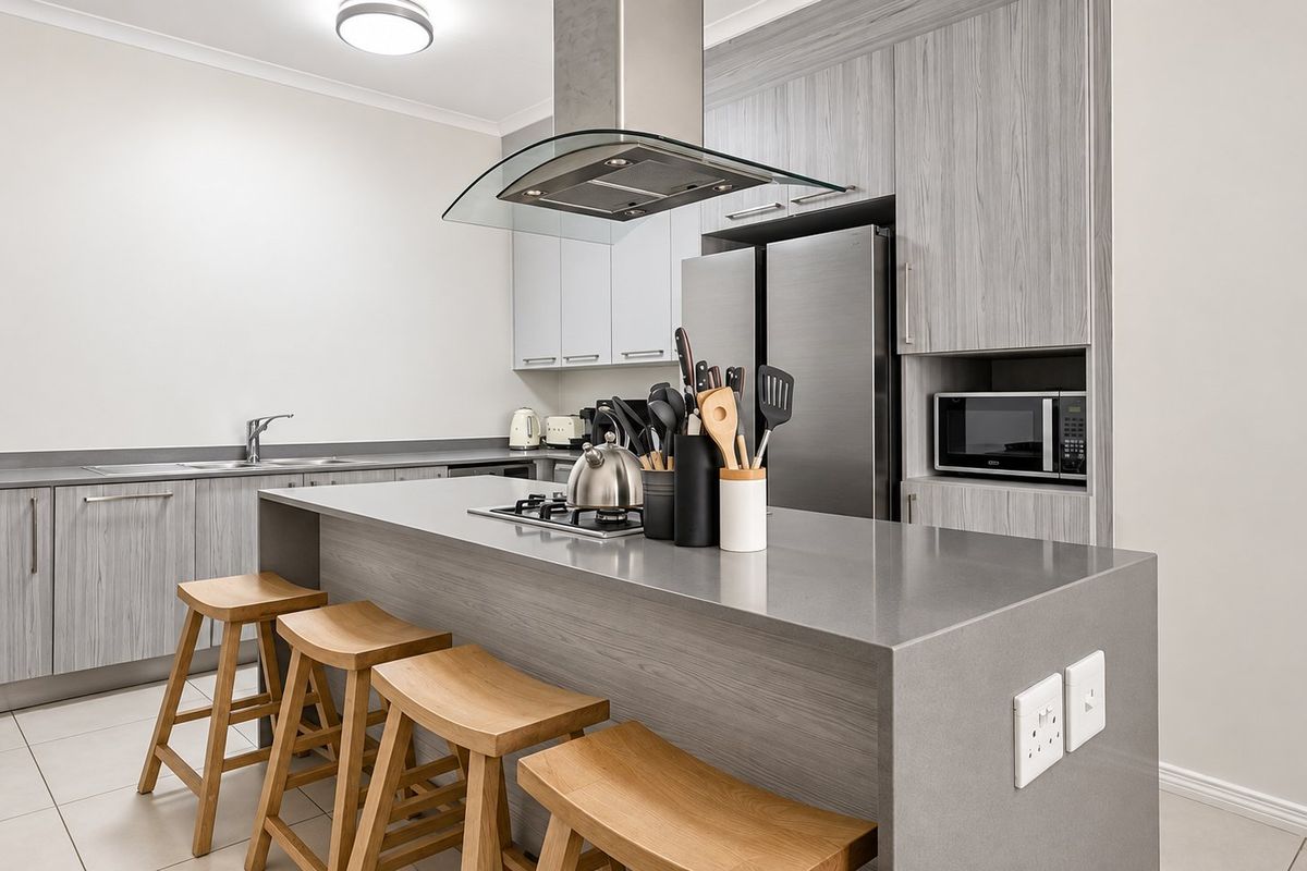 Modern kitchen featuring a central island with stone countertops, sleek wood-grain cabinetry, stainless steel appliances, and tiled flooring.