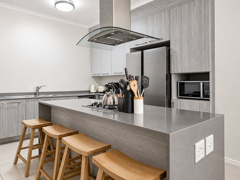 Modern kitchen featuring a central island with stone countertops, sleek wood-grain cabinetry, stainless steel appliances, and tiled flooring.