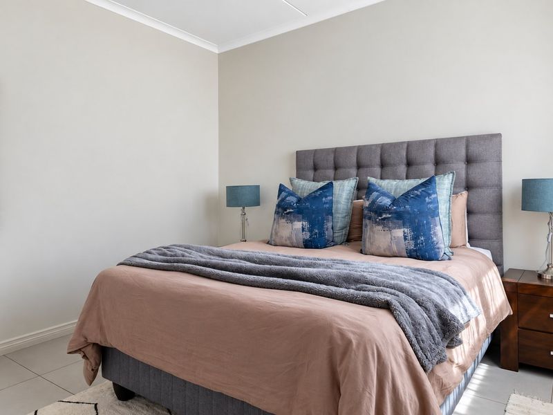 A well-maintained bedroom featuring neutral wall tones, tiled flooring, and coved ceiling detailing, providing a clean and comfortable living space.