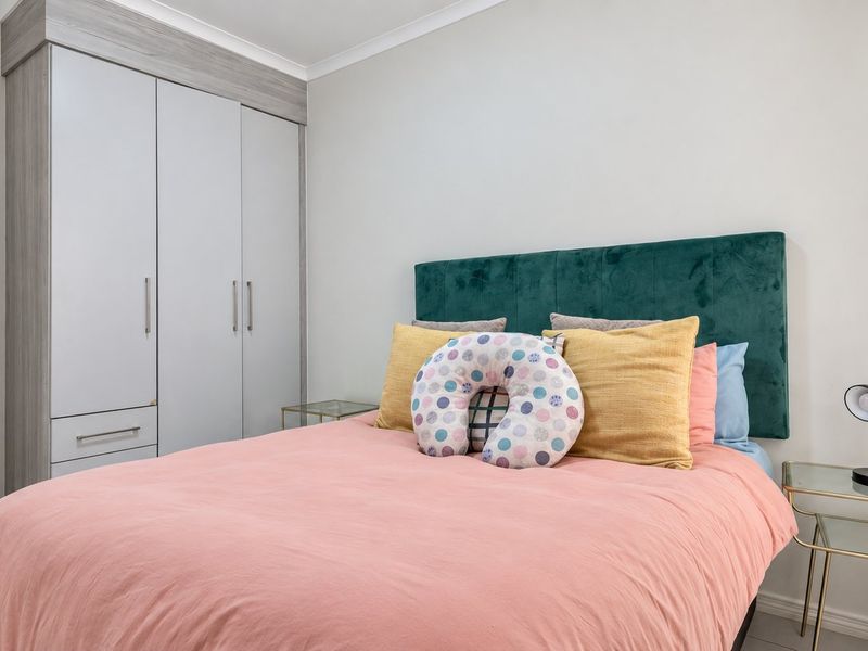 A well-maintained bedroom featuring a neutral color palette, built-in wardrobes with modern finishes, and clean architectural lines.