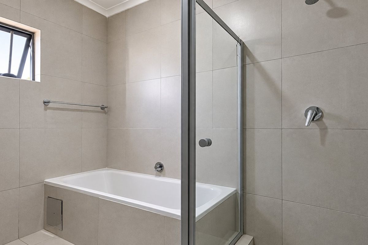 Modern bathroom featuring a built-in bathtub, separate shower enclosure with glass screen, and neutral large-format wall tiling.
