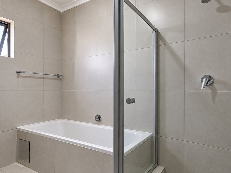 Modern bathroom featuring a built-in bathtub, separate shower enclosure with glass screen, and neutral large-format wall tiling.