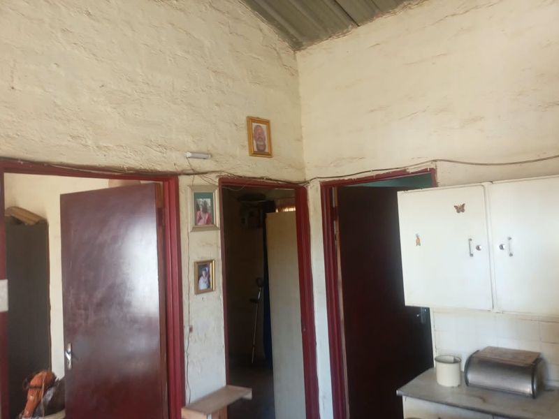 A hallway area featuring textured masonry walls, exposed corrugated metal ceiling, and built-in cabinetry, showing signs of significant wear and dated finishes.