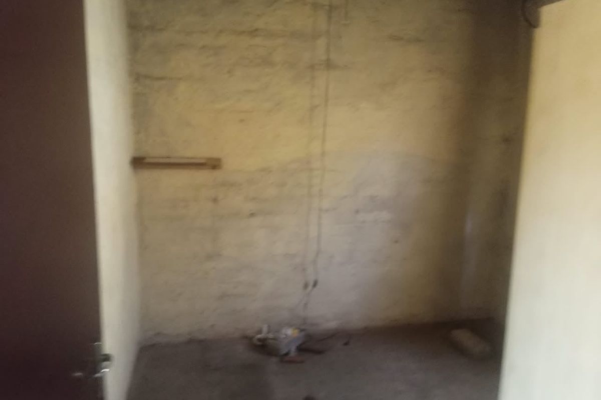 An unfinished utility space featuring exposed brick walls and visible electrical wiring, requiring significant renovation and finishing work.