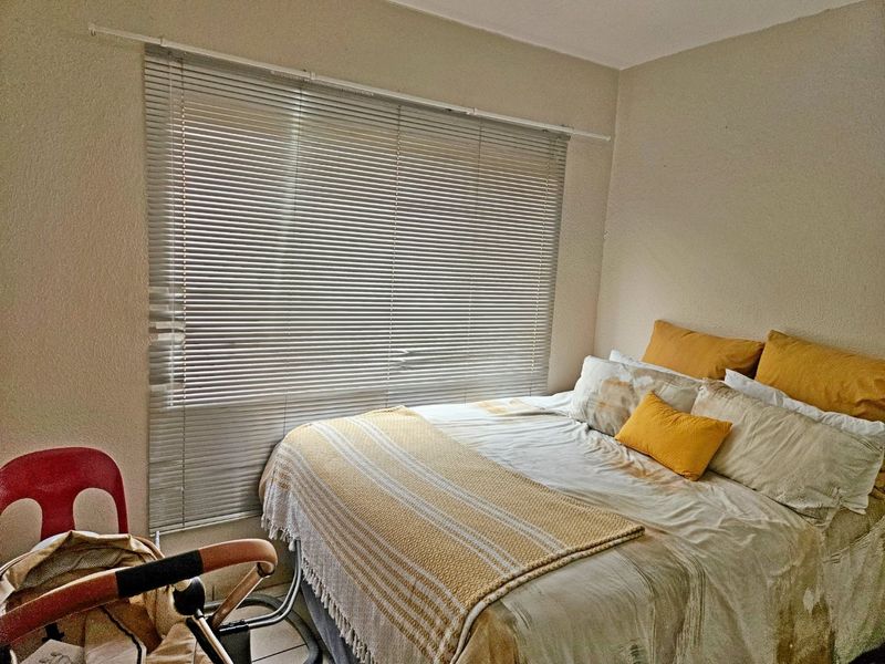 A standard bedroom featuring tiled flooring and fitted venetian blinds, providing a functional space with neutral wall finishes.