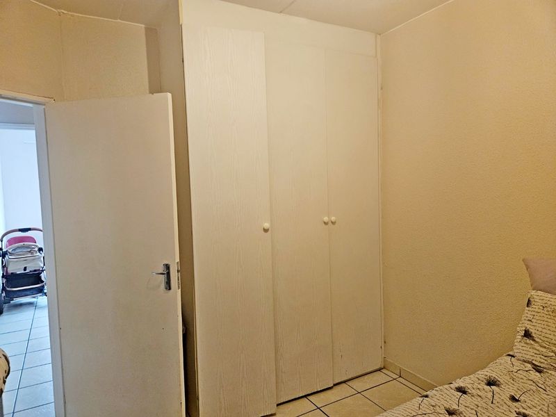 A bedroom featuring built-in wardrobes and tiled flooring, offering a functional space with potential for cosmetic updates.