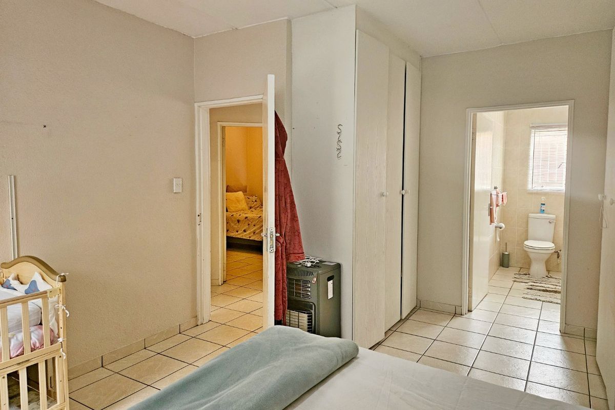 Bedroom featuring tiled flooring, built-in cupboards, and direct access to an en-suite bathroom.