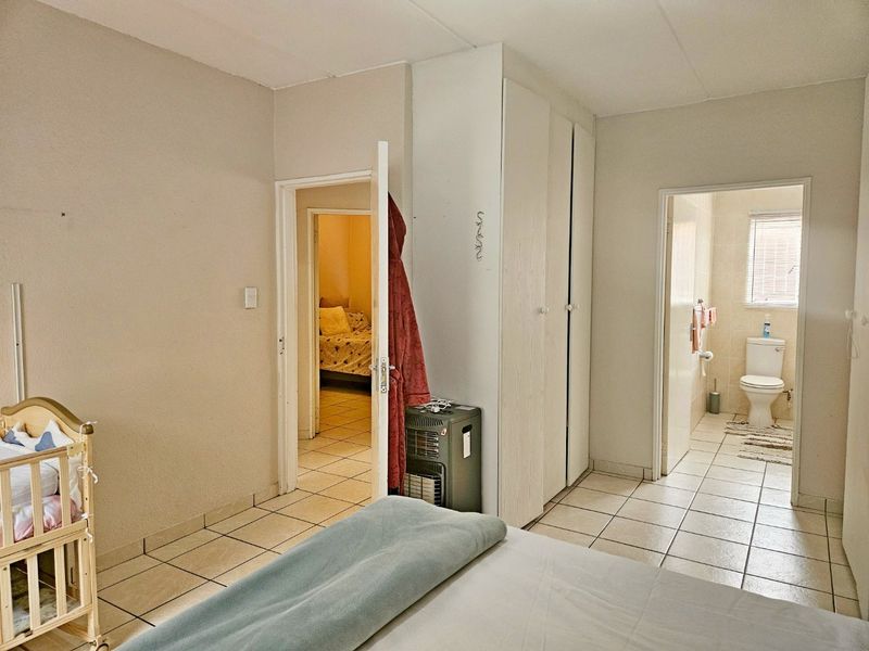 Bedroom featuring tiled flooring, built-in cupboards, and direct access to an en-suite bathroom.