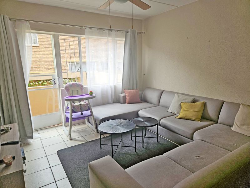 A living room featuring tiled flooring, a ceiling fan, and a sliding glass door providing access to the exterior.