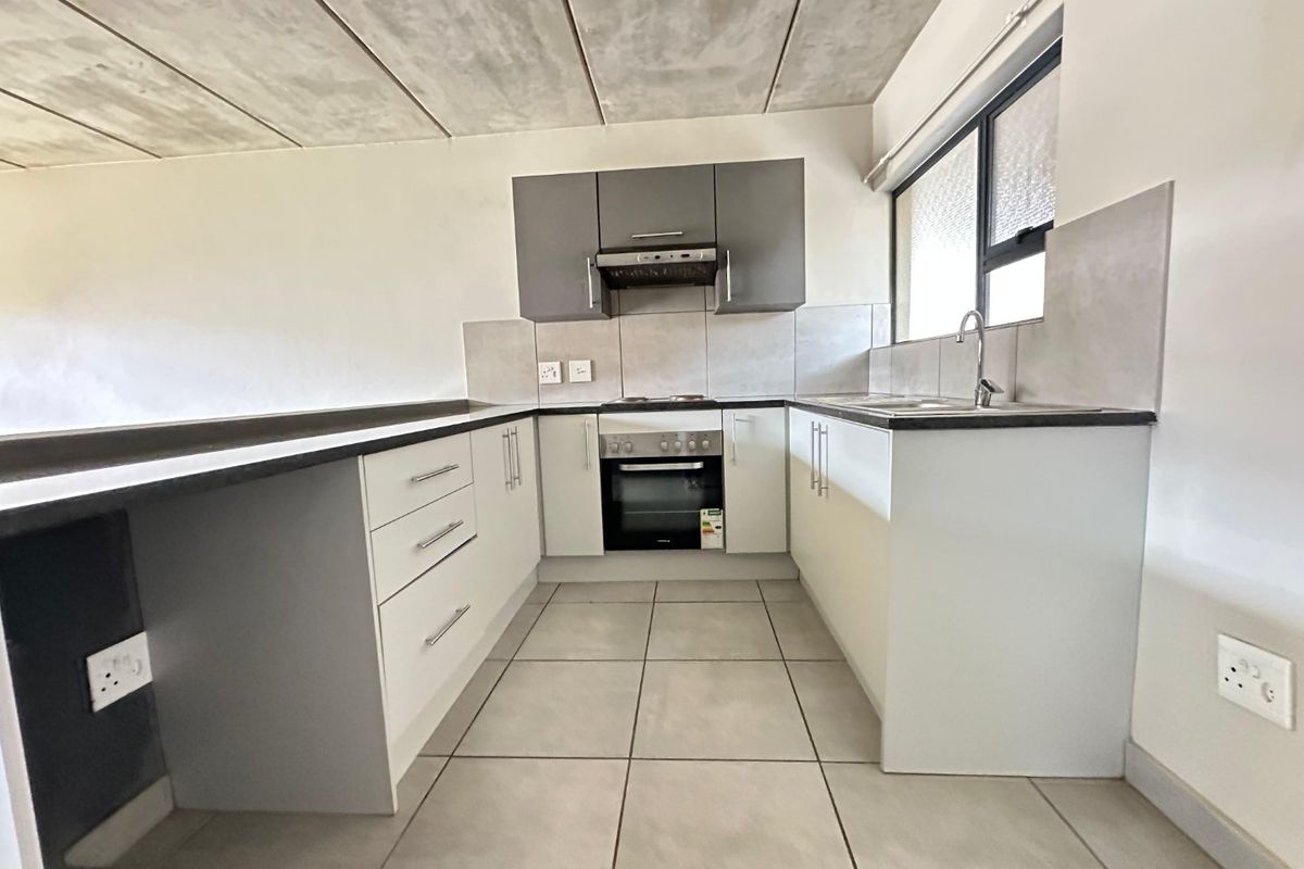 Modern kitchen featuring built-in cabinetry, integrated oven and hob, tiled backsplash, and an industrial-style exposed concrete ceiling.