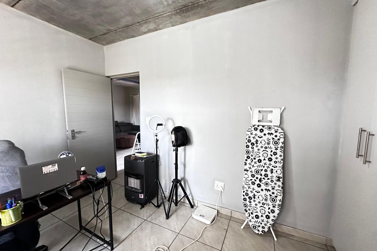 A bedroom featuring an exposed concrete ceiling, tiled flooring, and built-in storage, offering a neutral canvas for personalization.