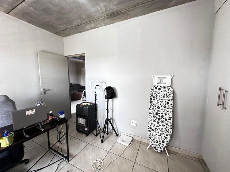 A bedroom featuring an exposed concrete ceiling, tiled flooring, and built-in storage, offering a neutral canvas for personalization.
