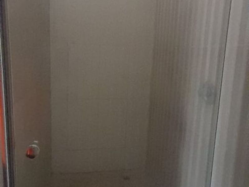 A functional shower stall featuring a modern rain shower head and tiled wall finishes within a bathroom space.