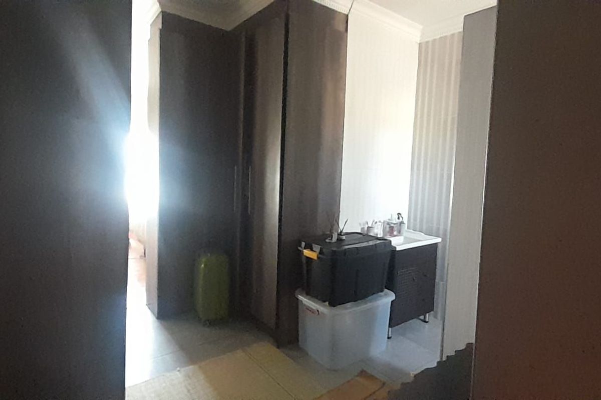 A bedroom area featuring built-in cupboards and a small vanity basin, offering functional storage and utility space.