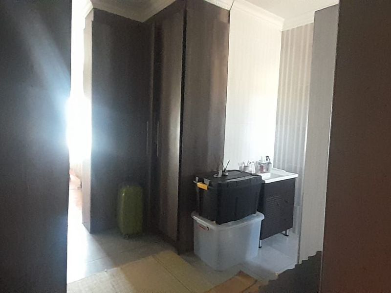 A bedroom area featuring built-in cupboards and a small vanity basin, offering functional storage and utility space.