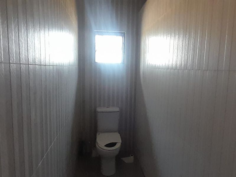 A compact bathroom featuring full-height wall tiling and a standard toilet fixture.