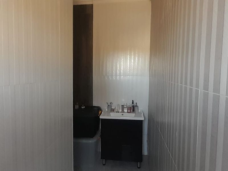 A compact bathroom featuring full-height wall tiling and a modern vanity unit with an integrated washbasin.