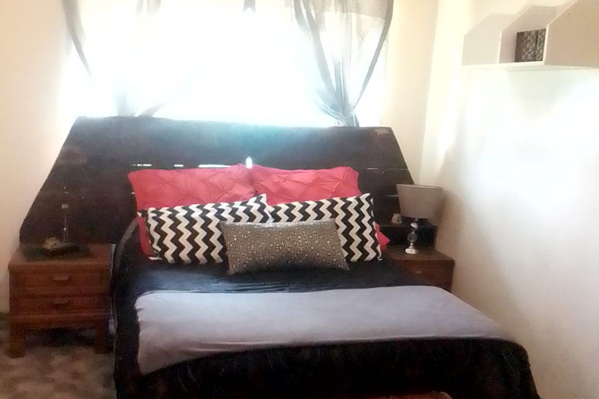 A bedroom featuring a window with natural light, built-in wall shelving, and a ventilation grille.