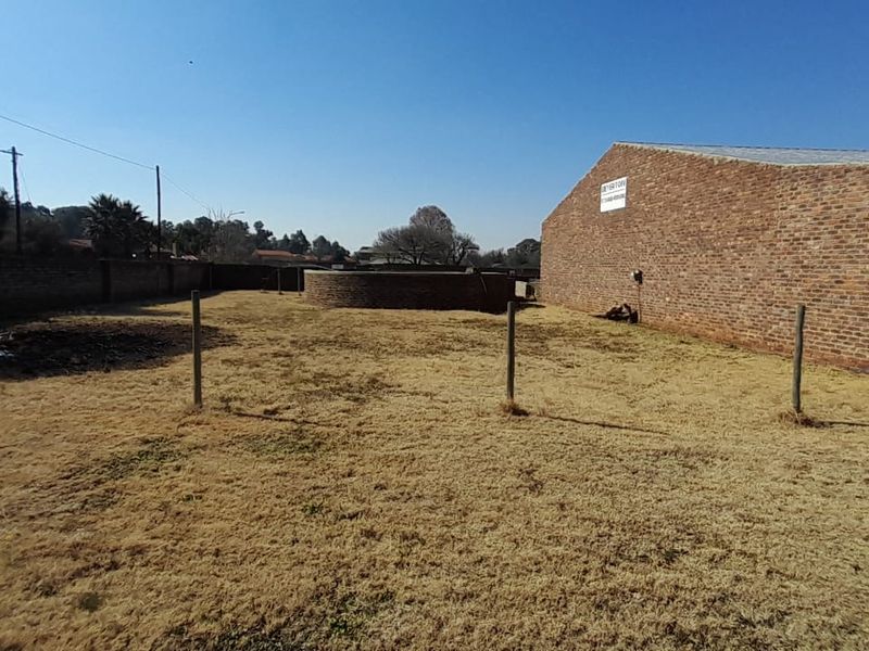 A spacious rear yard featuring a large brick building, a circular brick structure, and perimeter walling, offering significant potential for landscaping or development.