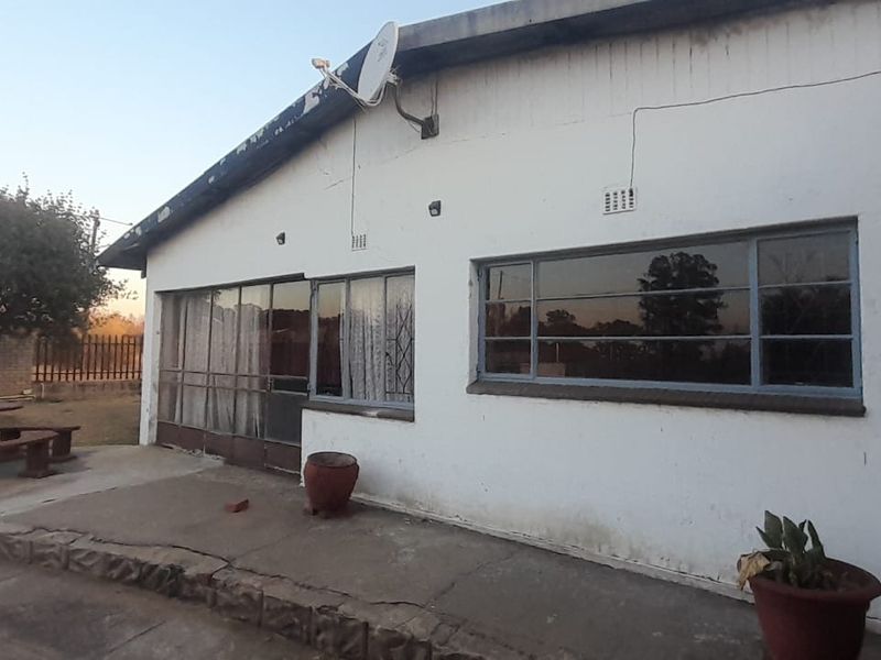 Rear exterior view of the house featuring a concrete patio area, steel-framed windows, and a satellite dish mounted on the roofline.