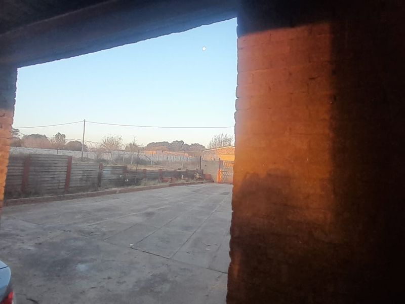 An open-sided garage structure featuring exposed brick pillars and a concrete floor, offering potential for secure parking or workshop space.