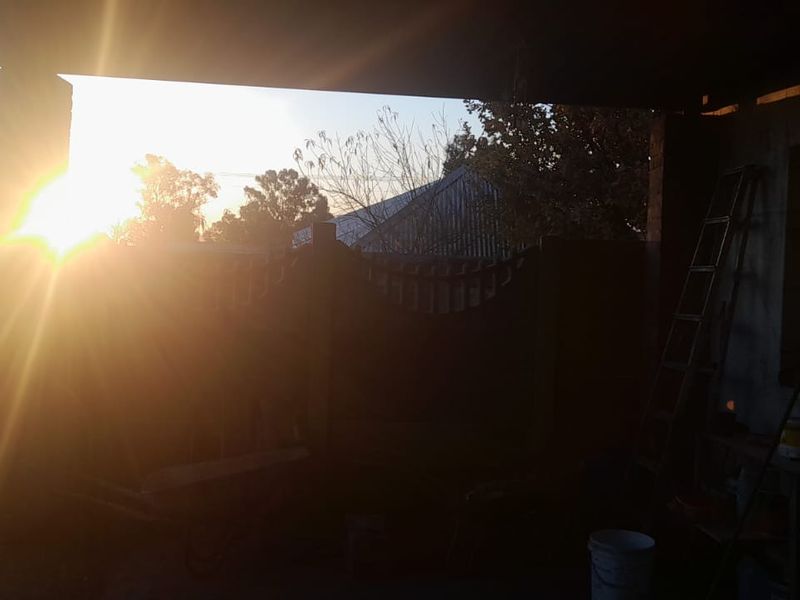 A covered outdoor patio area at sunset, showing basic structural masonry and a shaded exterior space.