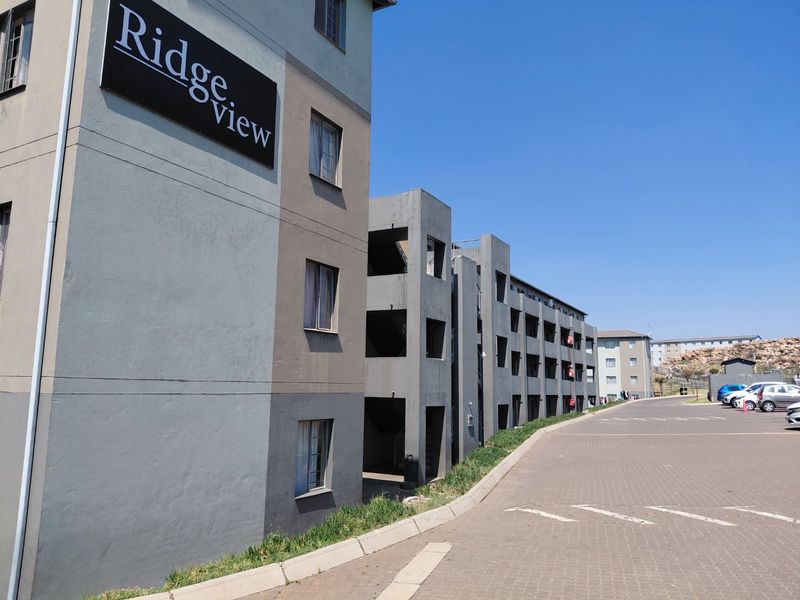Exterior view of the Ridgeview apartment complex featuring a paved driveway and multi-story residential building facade.