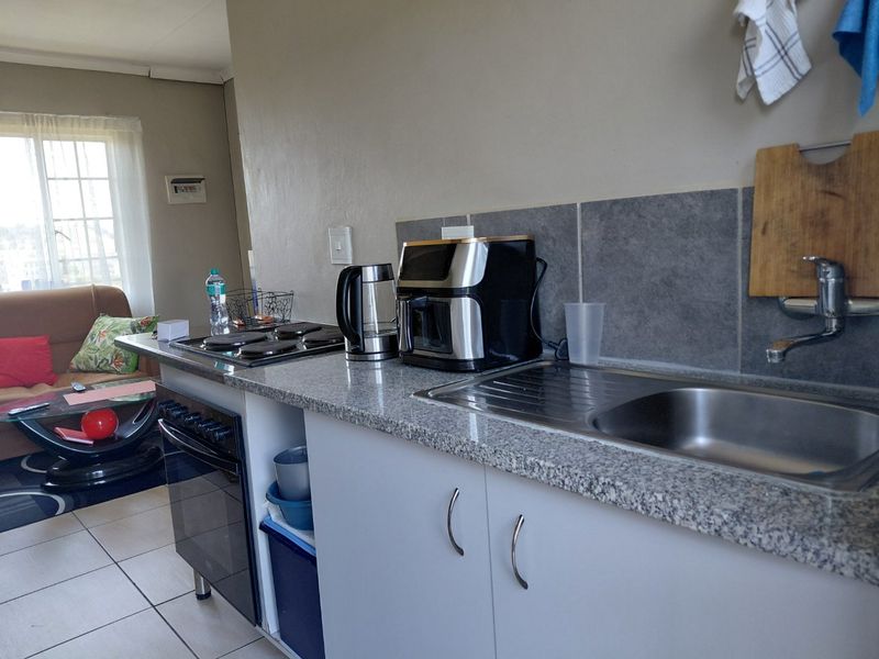 Open-plan kitchen area featuring a granite countertop, stainless steel sink, built-in oven, and electric hob, seamlessly connected to the living space.