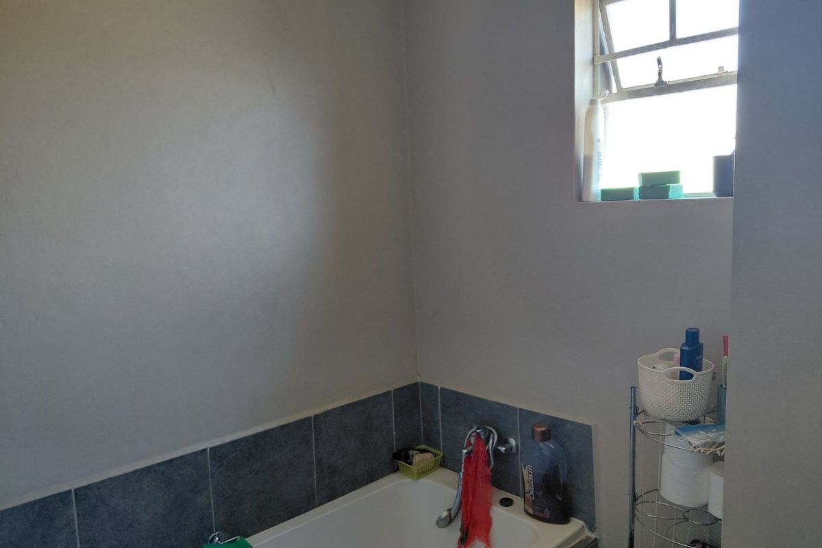 A functional bathroom featuring a bathtub with tiled splashback and a top-hung window for natural light and ventilation.