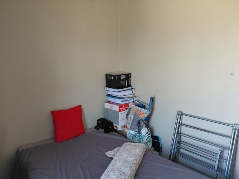 A simple bedroom space with neutral wall finishes, suitable for a single bed setup.
