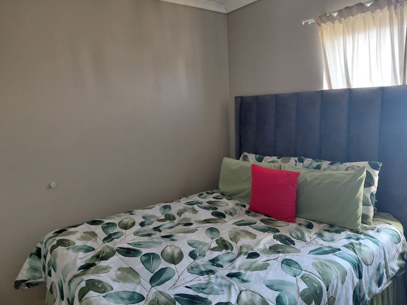 A standard bedroom featuring neutral wall tones, coving, and a window with a fitted curtain rail.