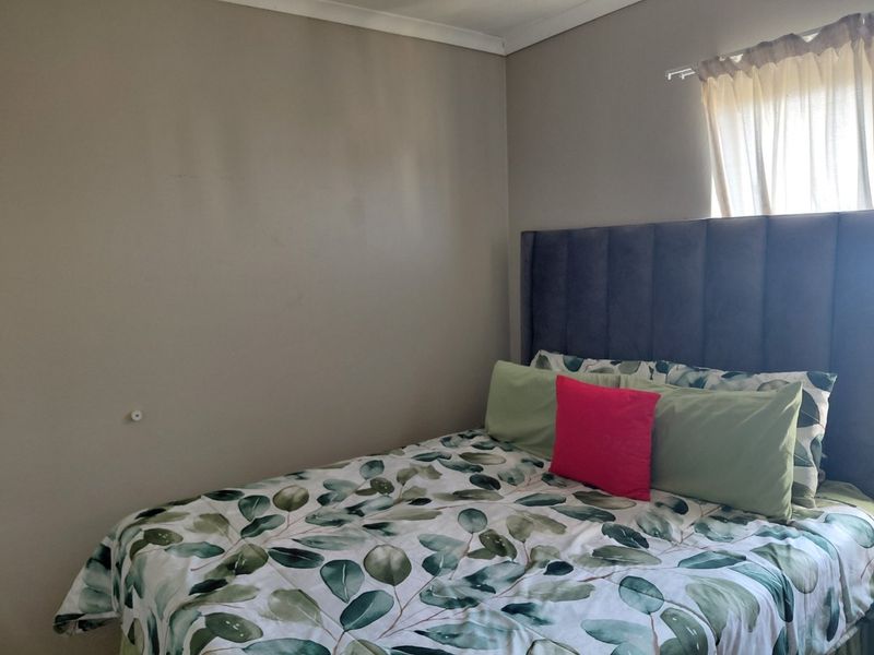 A simple bedroom featuring neutral wall tones, coving, and a window with a fitted curtain rod.
