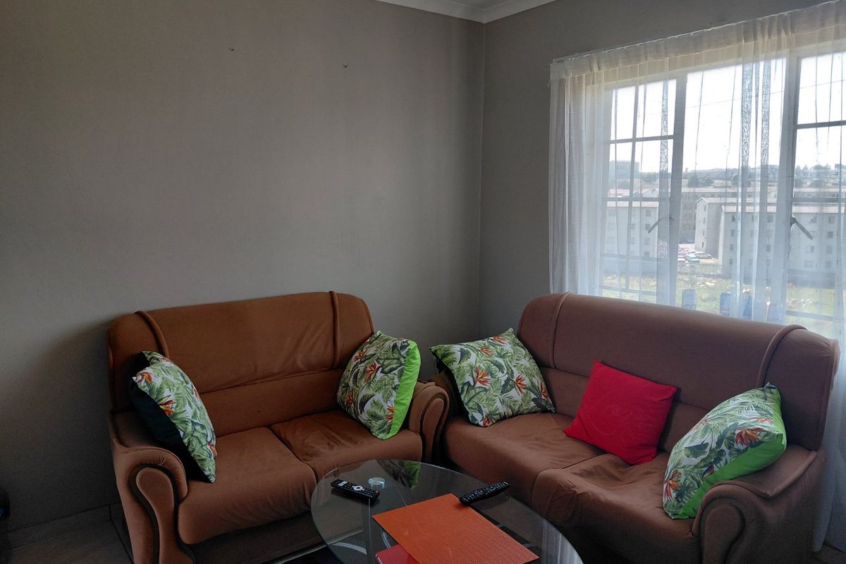 A living room area featuring tiled flooring, a window with security bars, and neutral wall paint.