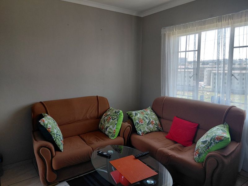 A living room area featuring tiled flooring, a window with security bars, and neutral wall paint.