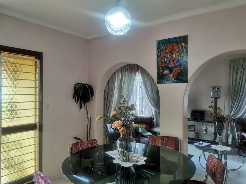Dining area featuring distinctive arched doorways, tiled flooring, and a security gate, providing a functional space with traditional architectural character.