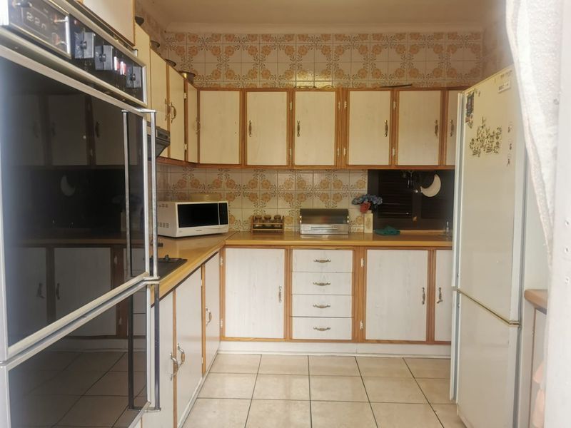 A functional kitchen featuring built-in oven, laminate countertops, and tiled backsplash, offering a dated aesthetic ready for modernization.